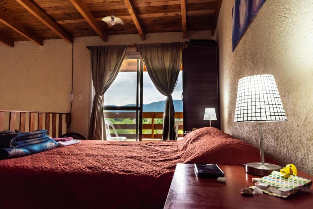 a bedroom with a bed with a table and a window at Tierras de Shiva in Valle Hermoso