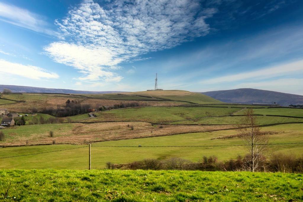 a green field with a cross on top of a hill at THE VIEW! in Delph