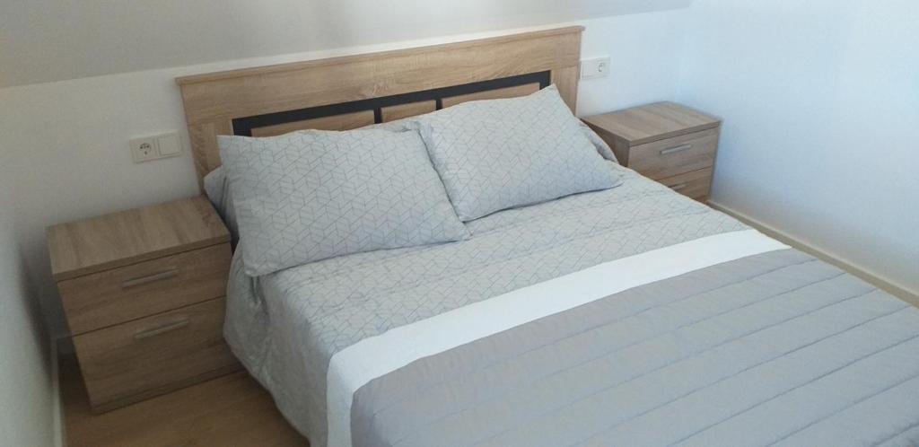 1 dormitorio con 1 cama blanca y 2 mesitas de noche en APARTAMeNTOS DON MANUEL A en Cee