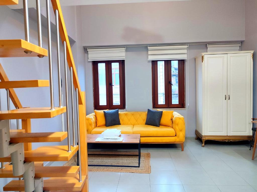 ein gelbes Sofa im Wohnzimmer mit Fenstern in der Unterkunft Cozy Duplex House-Near Taksim-Home Design in Istanbul