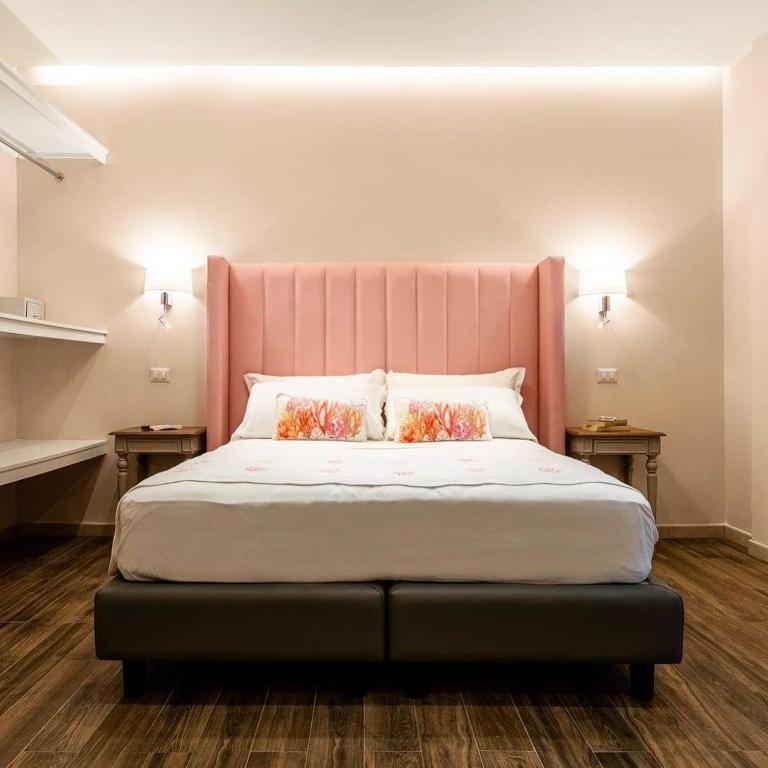 a bedroom with a large bed with a pink headboard at Onda Marina Suites in Cagliari
