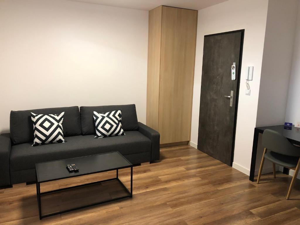 a living room with a black couch and a table at Apartamenty Platinex 6 in Krakow
