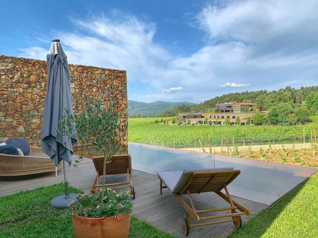 a patio with an umbrella and chairs and a pool at Monverde - Wine Experience Hotel - by Unlock Hotels in Amarante