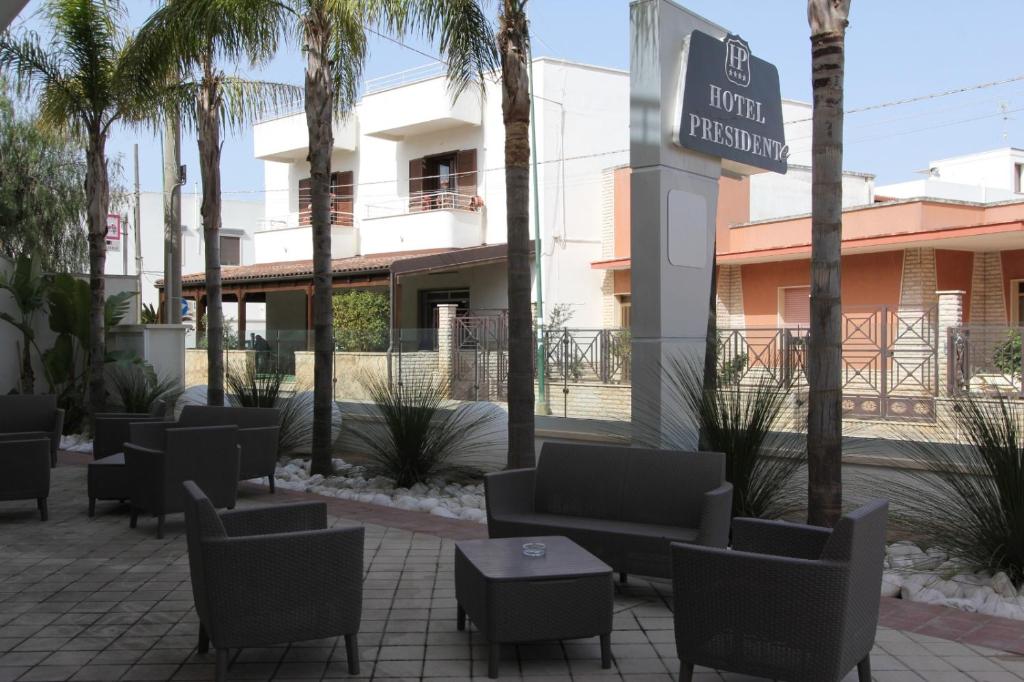 a hotel with chairs and tables and palm trees at Hotel Presidente in Porto Cesareo