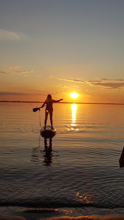 eine Person auf einem Paddelbrett im Wasser bei Sonnenuntergang in der Unterkunft OstSEESTERNchen Zempin in Zempin