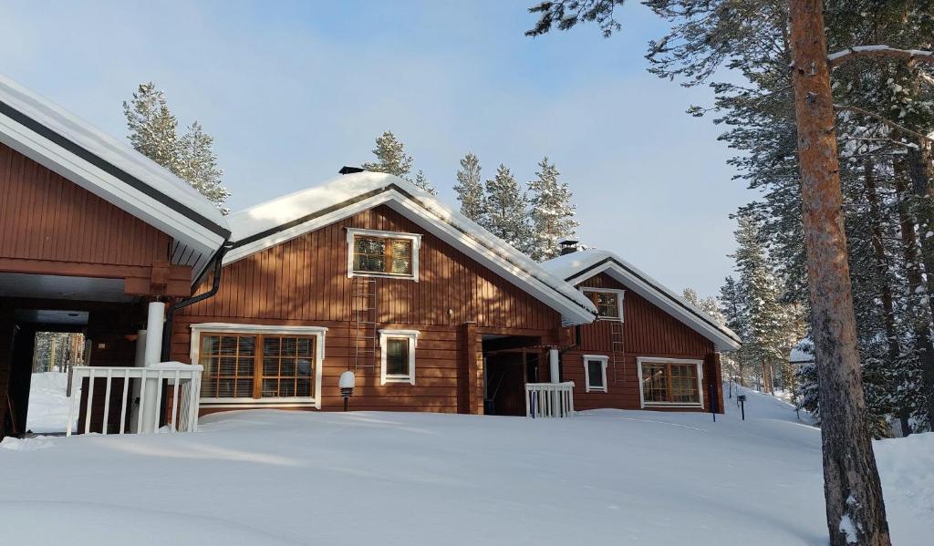 une maison en bois dans la neige avec des arbres dans l'établissement Villiporo Cabin Levi, à Levi