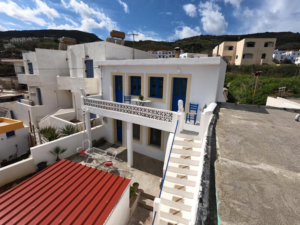 a white house with blue doors and a staircase at AGIAS PELAGIAS LITTLE BEACH HOUSE in Agia Pelagia