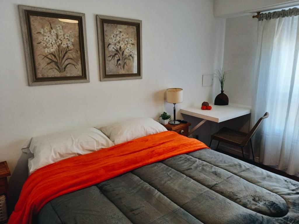 um quarto com uma cama com um cobertor laranja em Alto de Sarmiento em Tandil