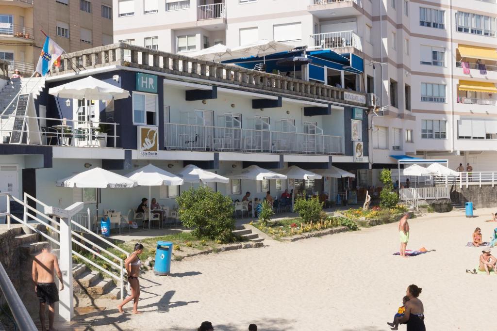 people on the beach in front of a hotel at O Son Do Mar in Sanxenxo