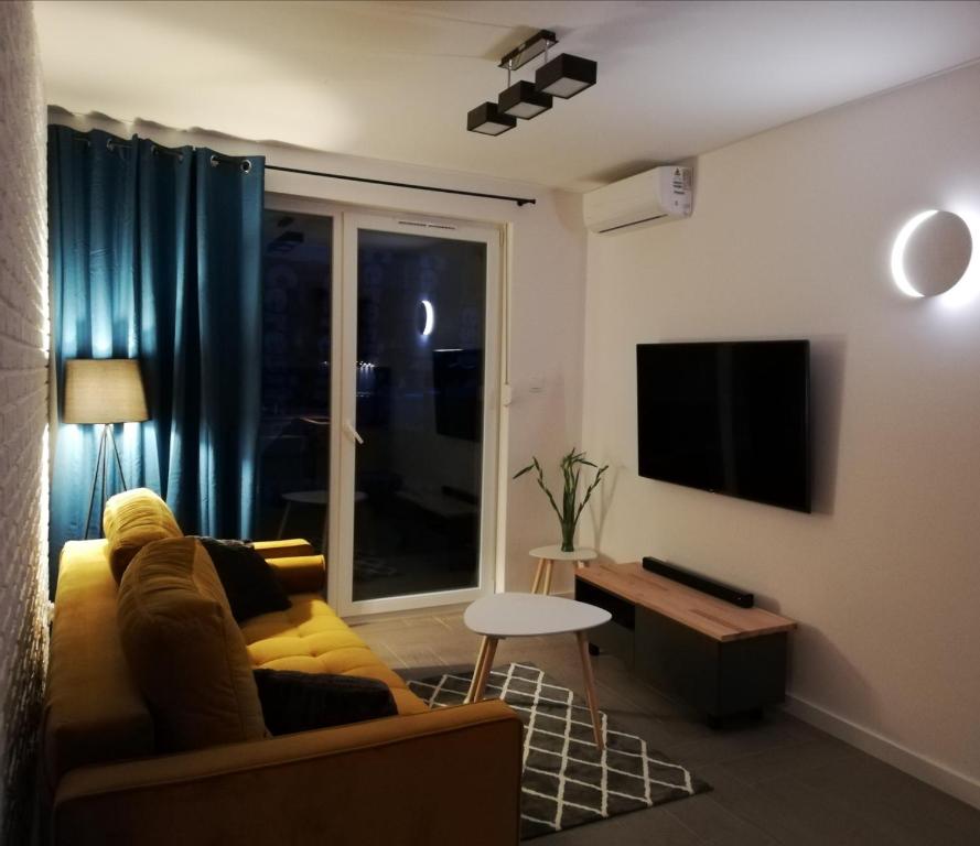 a living room with a couch and a tv at Apartament Sand&Blue in Sztutowo
