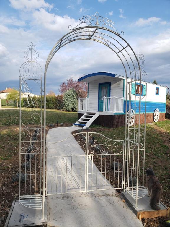 um portão com um gato sentado em frente a uma casa em Roule hôtes em Montéglin