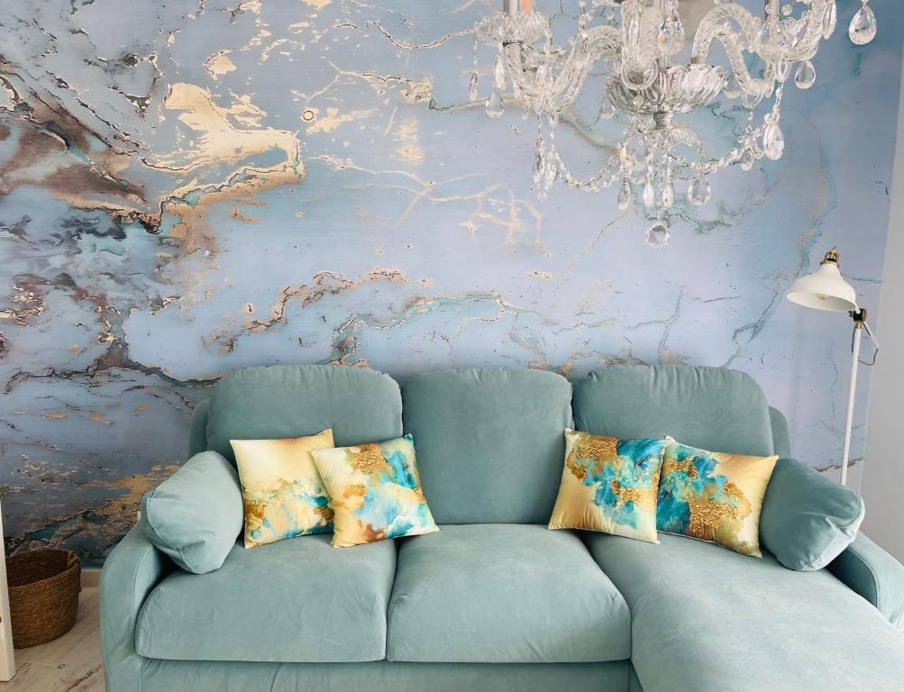 a blue couch in a living room with a chandelier at Blue House Mallorca in Ses Salines