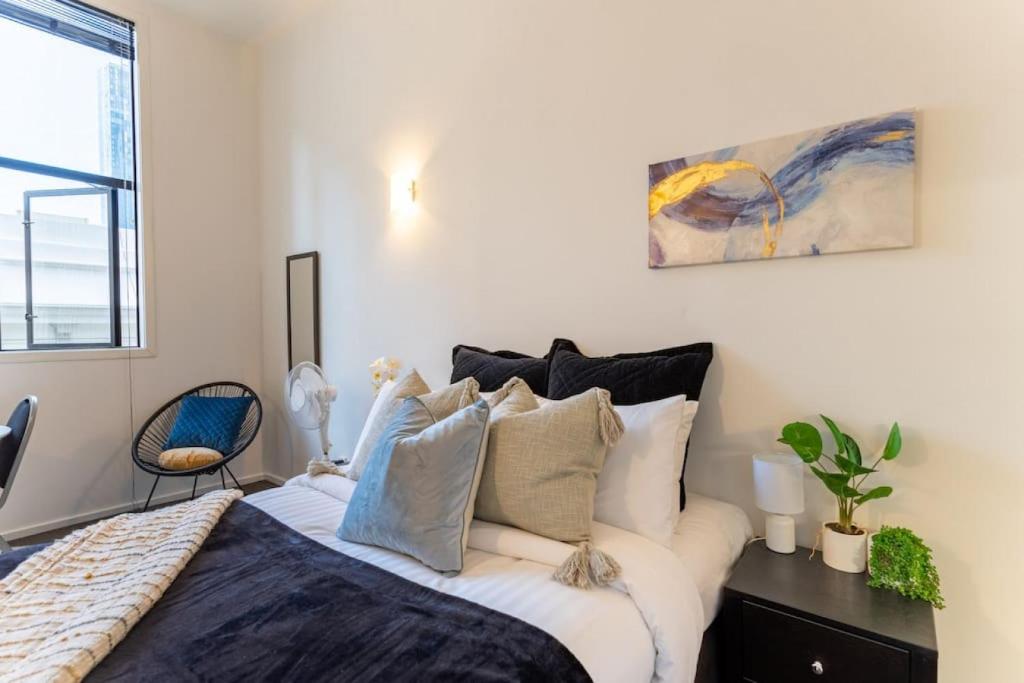 um quarto com uma cama grande e almofadas em Bright CBD Studio -Near SkyTower - WiFi - Cityscape em Auckland