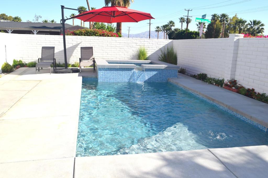 einen Pool mit einem Tisch und einem Sonnenschirm in der Unterkunft West Racquet Club Art Room in Palm Springs