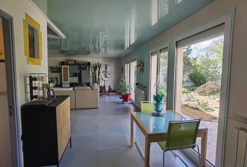 uma grande cozinha com uma mesa de vidro e cadeiras verdes em La Vie Est Belle, Chambre privée dans une villa em Trets