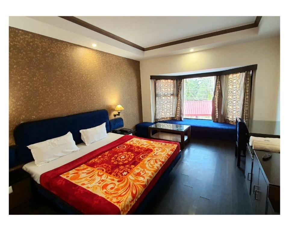 Drive Inn Dhanaulti في دانولتي: غرفة نوم بسرير واريكة ونافذة