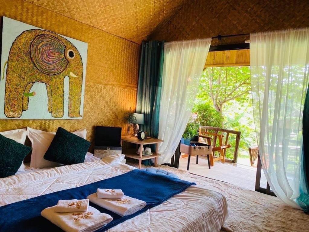 a bedroom with an elephant painting on the wall at 3 Pok Maewang jinxiang Gold elephant park in Ban Mae Sapok Noi