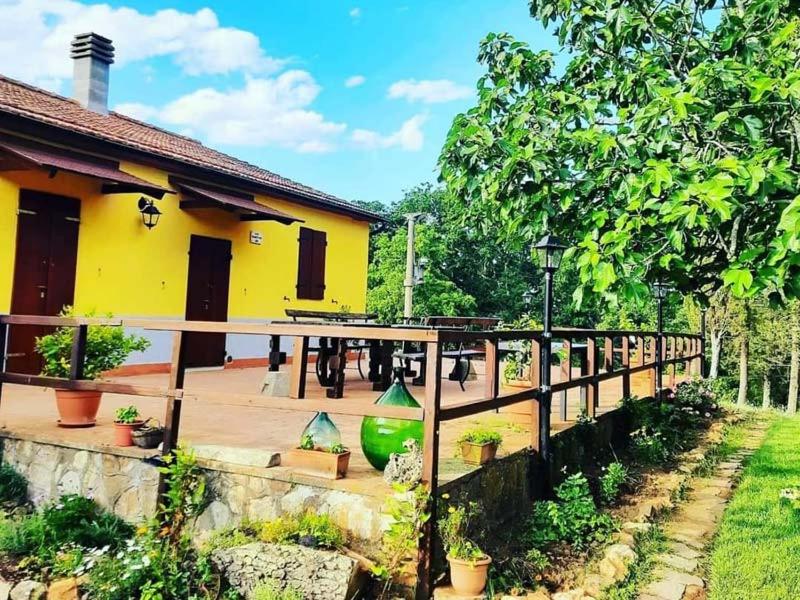 Casa amarilla con valla de madera y patio en Rifugio La Foresta, en Montioni Allumiera