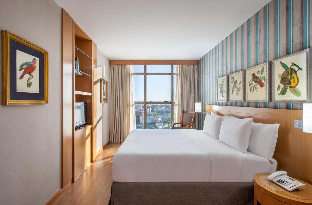 ブラジリアにあるBrasil 21 Suites Affiliated by Meliáの白いベッドと電話が備わるホテルルームです。