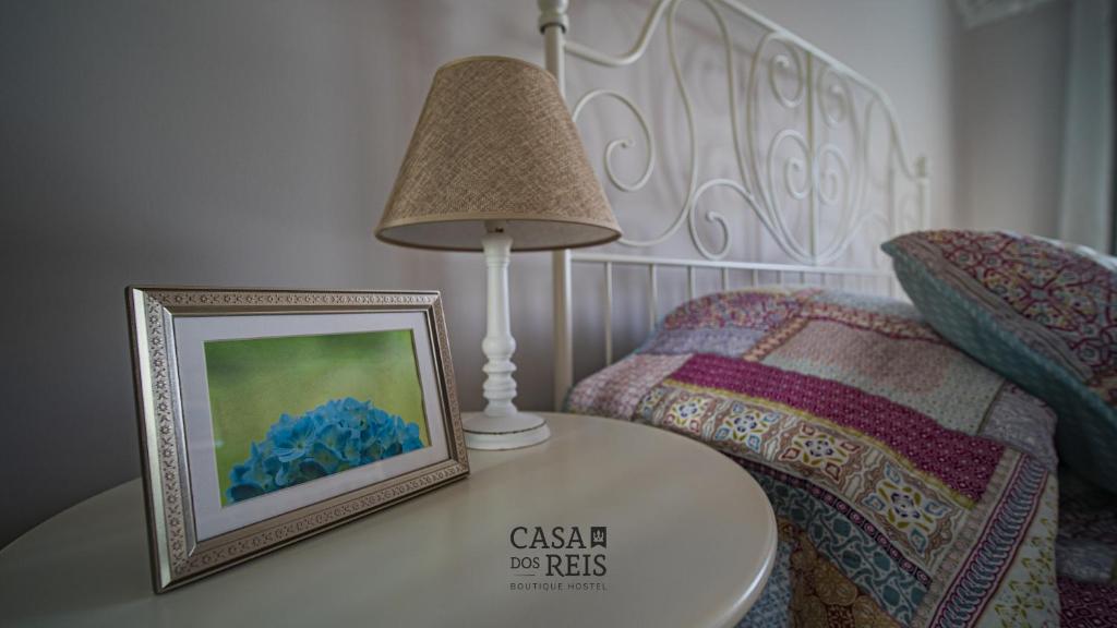 a table with a picture on it next to a bed at Casa Dos Reis - Boutique Hostel in Angra do Heroísmo