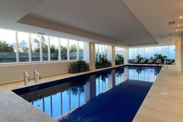 Beautiful Apartment at Carso Residential with Pool في مدينة ميكسيكو: مسبح كبير في مبنى كبير به نوافذ
