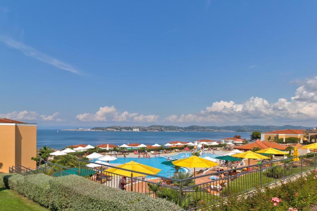 ein großer Pool mit Sonnenschirmen und dem Meer in der Unterkunft InBlue in Savudrija