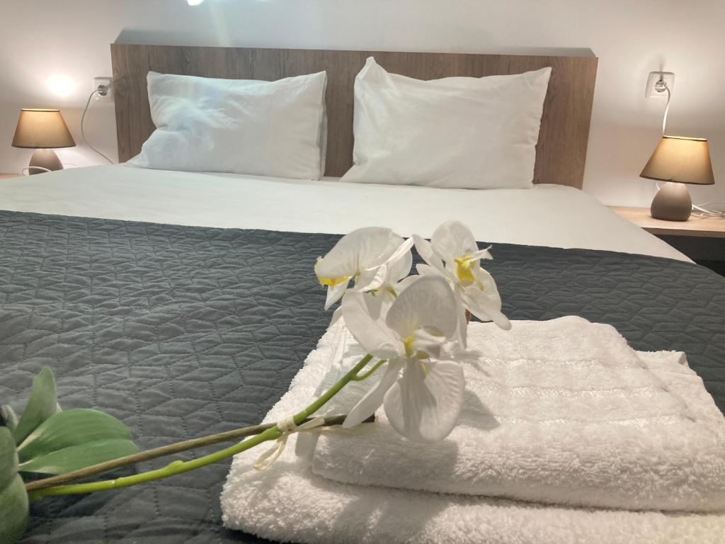 ein Hotelzimmer mit einem Bett mit weißen Handtüchern und Blumen in der Unterkunft Къща за гости Мегдана in Sopot