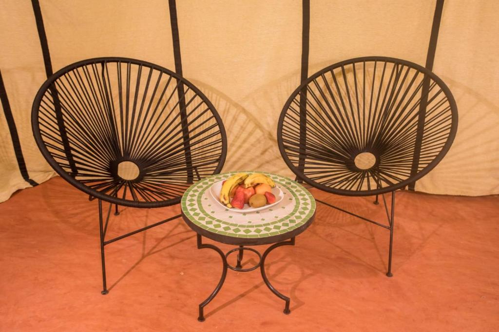two chairs with a plate of fruit on a table at Luxury Desert Camp Amanar in Merzouga