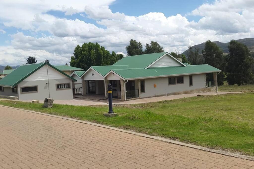 a row of houses with green roofs on a road at 8sIndoor indoor pool4 bedroom villaGreat view and backup power in Clarens