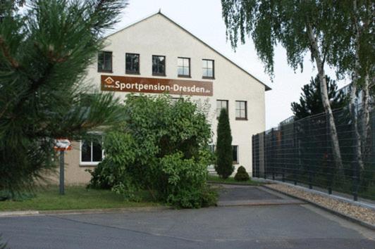 a white house with a sign in front of it at Sportpension Dresden in Dresden