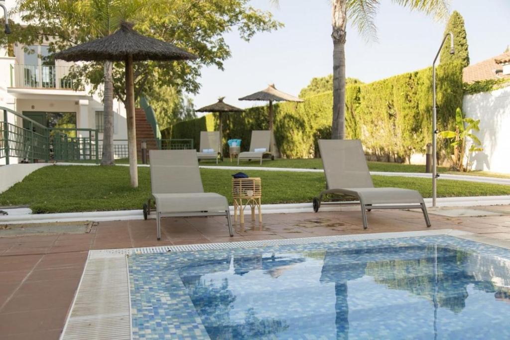 een zwembad met 2 stoelen en een parasol bij Apartamentos Brillante 156 in Córdoba