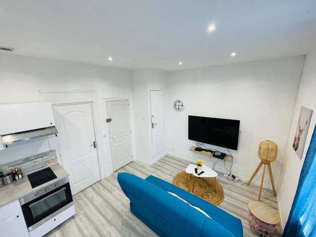 un salon avec un canapé bleu et une télévision dans l'établissement Appartement Nid Douillet Plus, à Tourcoing
