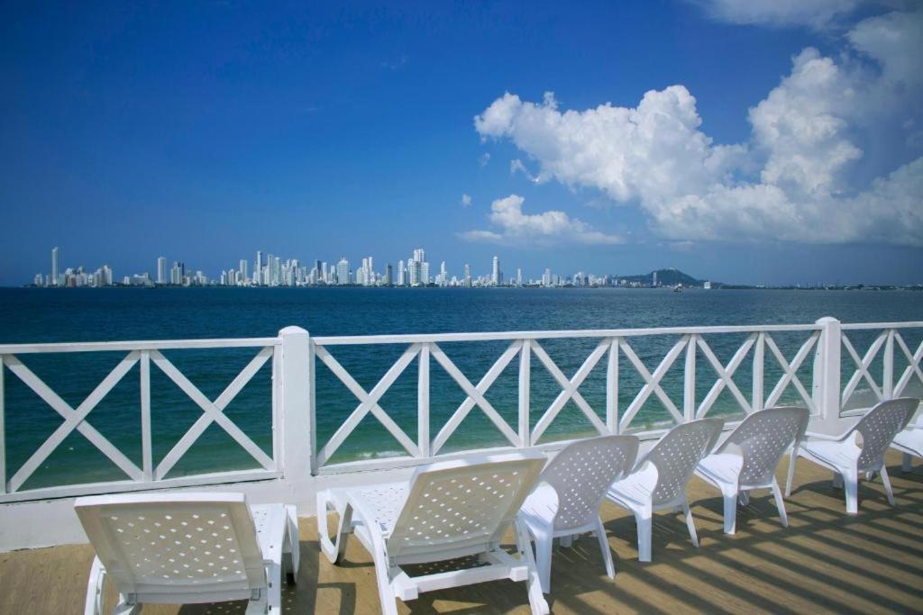 una fila de sillas en un balcón con vistas al agua en Hotel Dorado Plaza Punta Arena, en Tierra Bomba