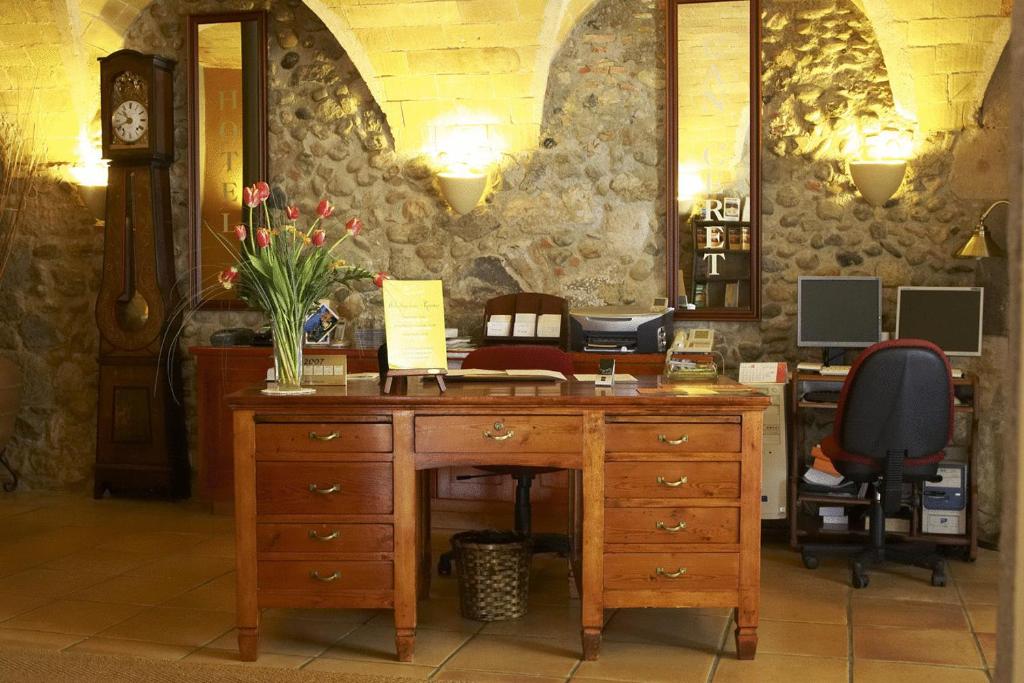 una oficina con un escritorio de madera con un jarrón de flores. en Hotel Can Ceret, en Sant Pere Pescador