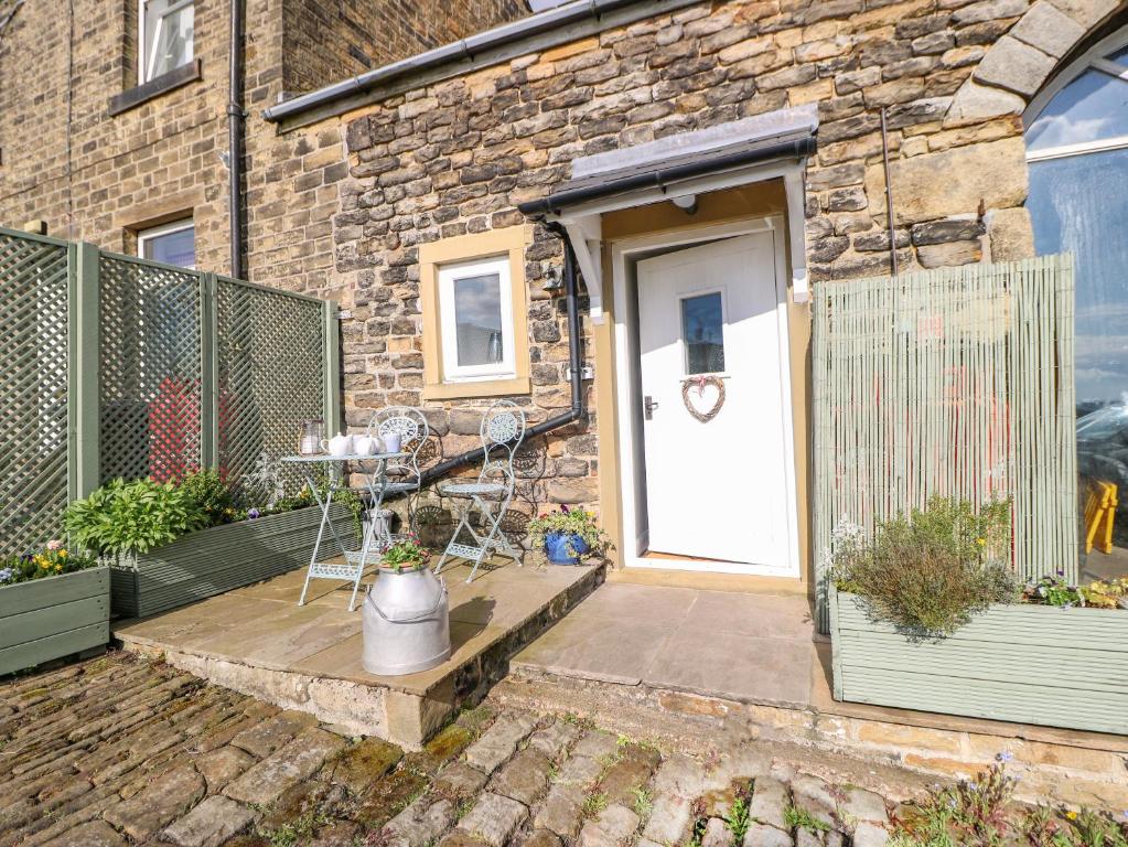 uma porta da frente de uma casa de tijolos com uma mesa em The Mistle Carr Farm em Ripponden