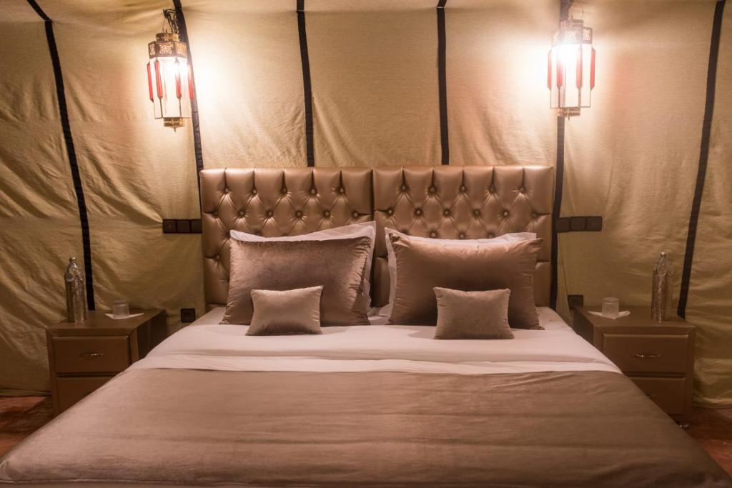 a bedroom with a large bed with three pillows at Luxury Desert Camp Amanar in Merzouga