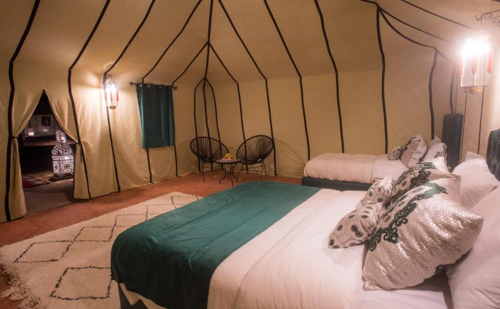 a bedroom with two beds in a tent at Luxury Desert Camp Amanar in Merzouga