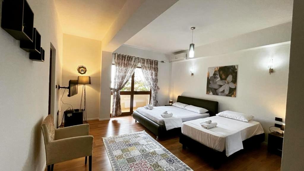 una habitación de hotel con dos camas y una silla en Hotel Ambasador Garden, en Lezhë
