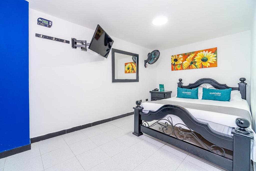 - une chambre avec un lit et une télévision murale dans l'établissement Ayenda Don Jorge de la 23, à Tuluá