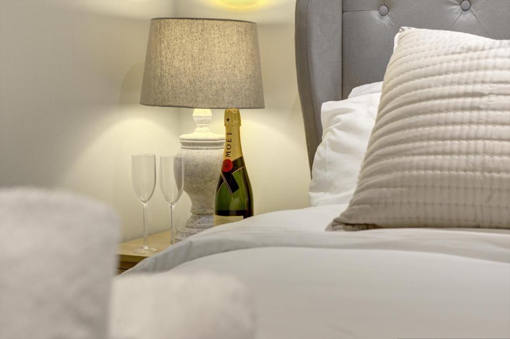 a bed with a bottle of wine and two glasses at Kist Accommodates - The Woodlands in Harrogate