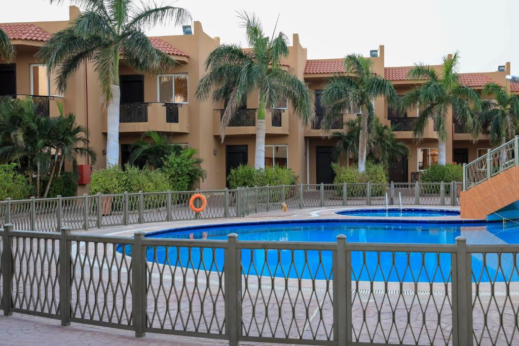 une piscine en face d'un bâtiment avec des palmiers dans l'établissement Alahlam Resort Yanbu, à Yanbu