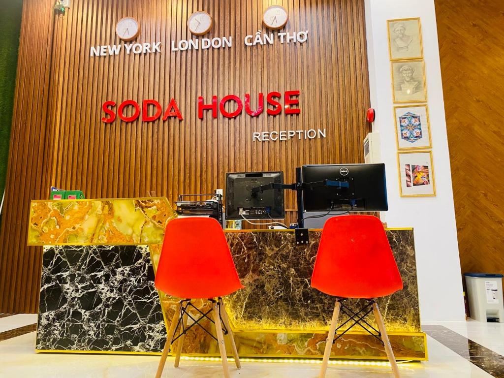 two red chairs in front of a saoda house reception at Soda House Cần Thơ in Can Tho