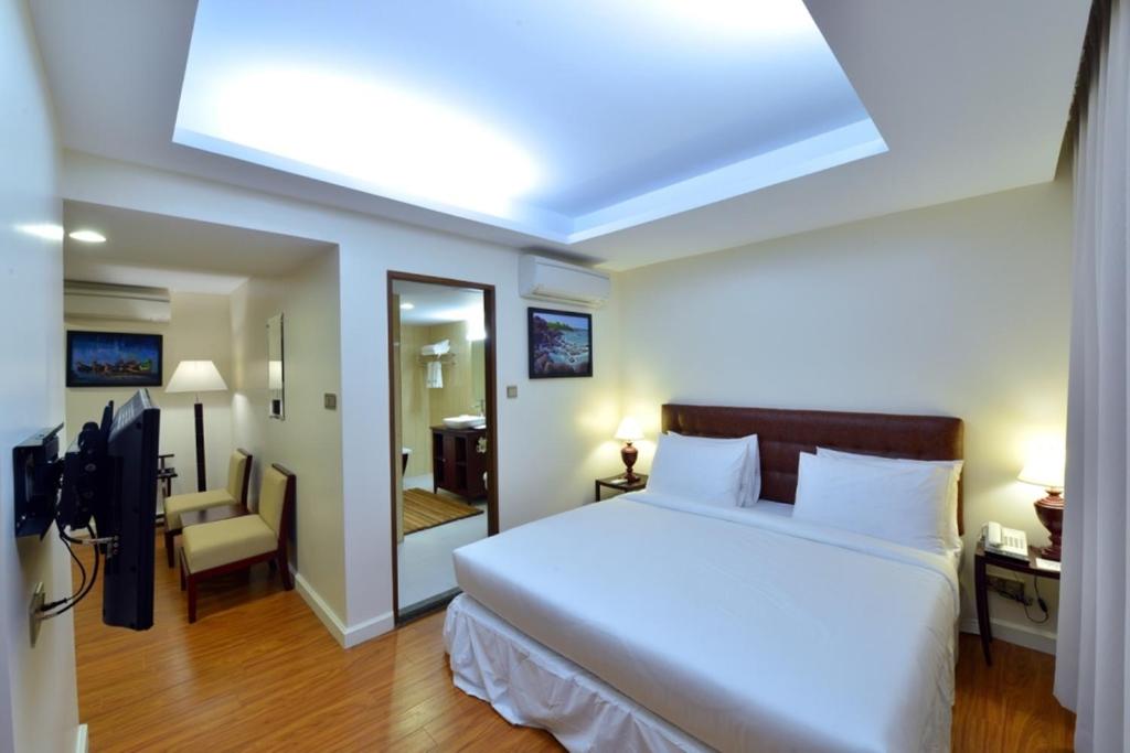 a bedroom with a large white bed with a skylight at Hotel KBA in Yangon