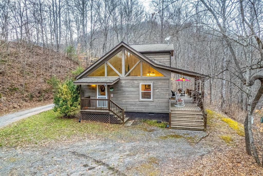 una pequeña casa en el bosque con porche en Tree Top Cabin, en Sylva