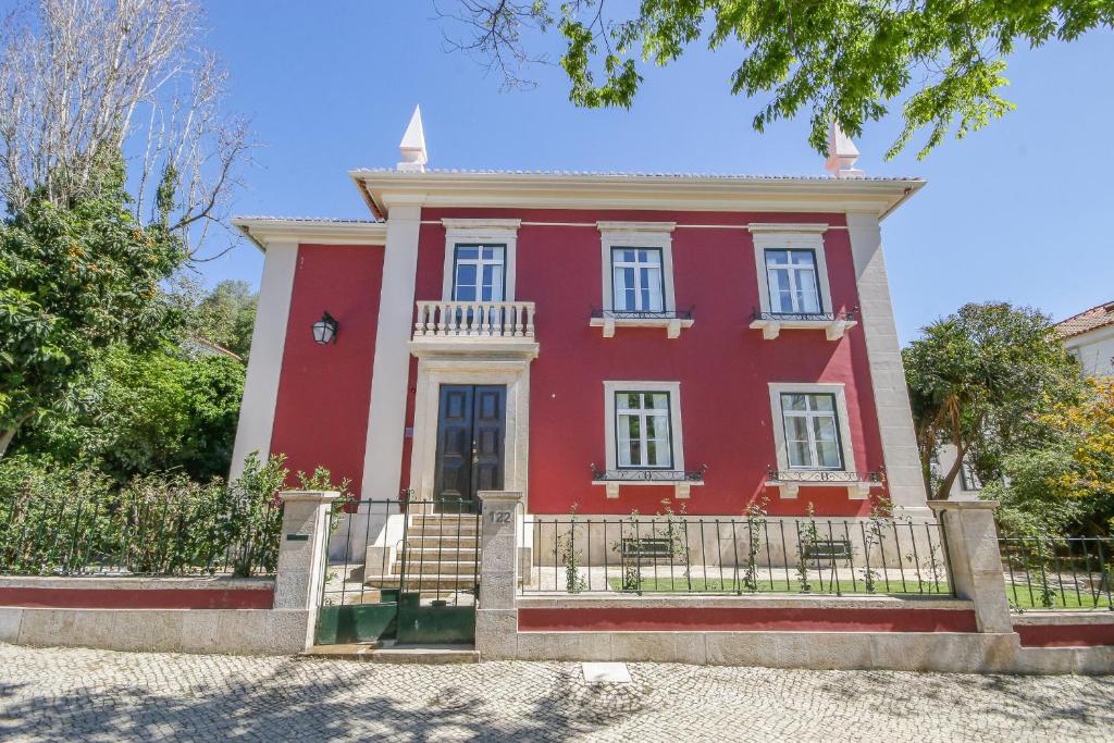 une maison rouge avec une clôture devant elle dans l'établissement Alvalade Palace, à Lisbonne