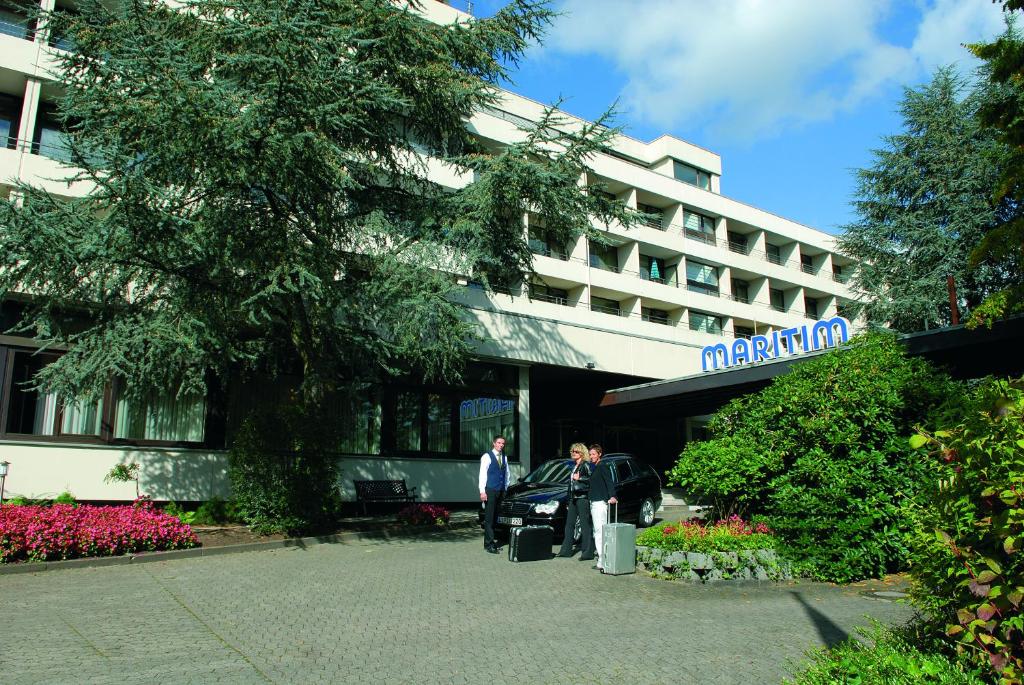 een man die voor een hotel staat met een auto bij Maritim Hotel Bad Salzuflen in Bad Salzuflen