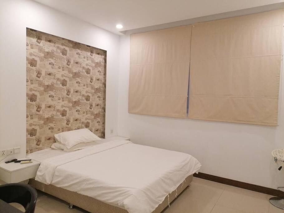 a bedroom with a white bed and a brick wall at Self-check-in private studio apartment in Phnom Penh