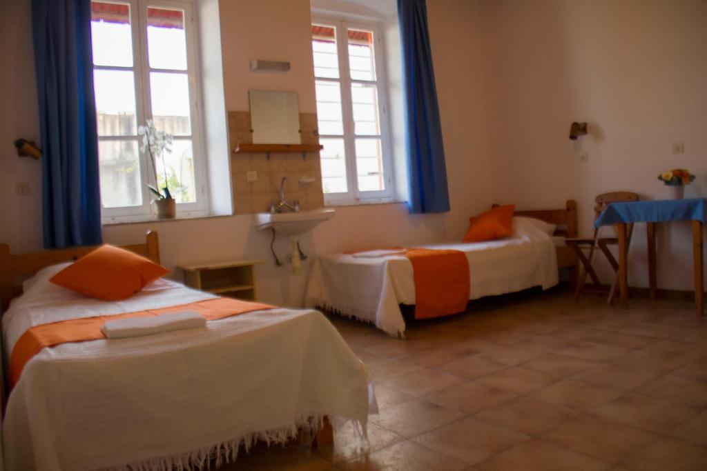 a room with two beds and a sink and two windows at Medieval Rose Guest House in Rhodes Town