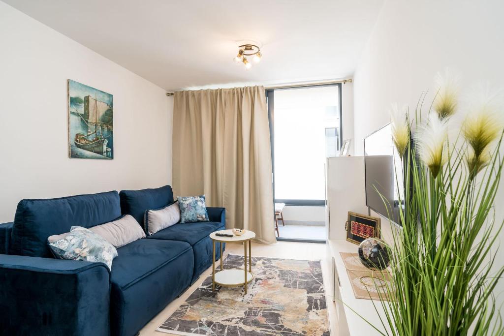 un salon avec un canapé bleu et une télévision dans l'établissement Apartment NAVA - new and spacious gem in the port, à Dubrovnik