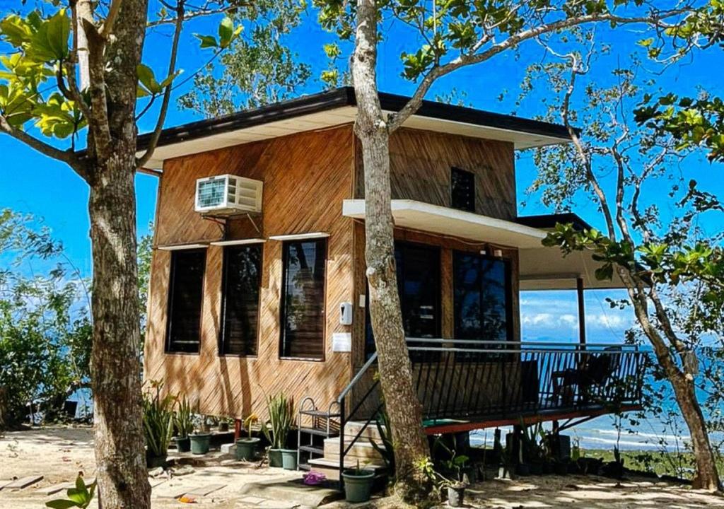 a wooden house with a balcony and trees at Tabique by the sea in Cebu City